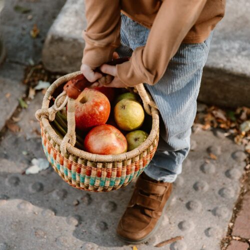 Boy holding apples in a small round Ghana market basket
