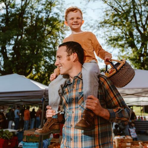 Young Boy with his father at an outdoor market using a small round basket