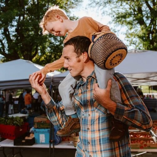 Father handing his son an apple in a market