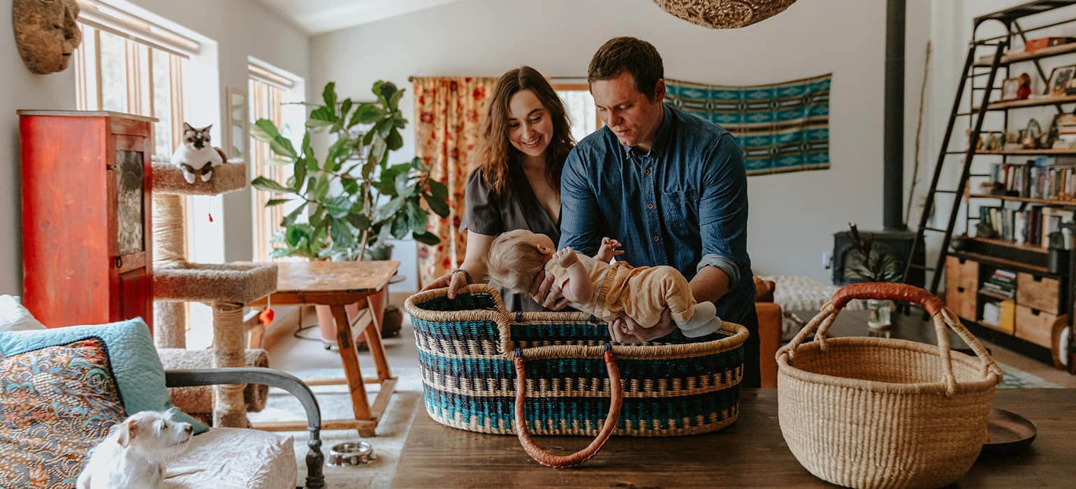 Father lifting baby into Moses Basket in a family home
