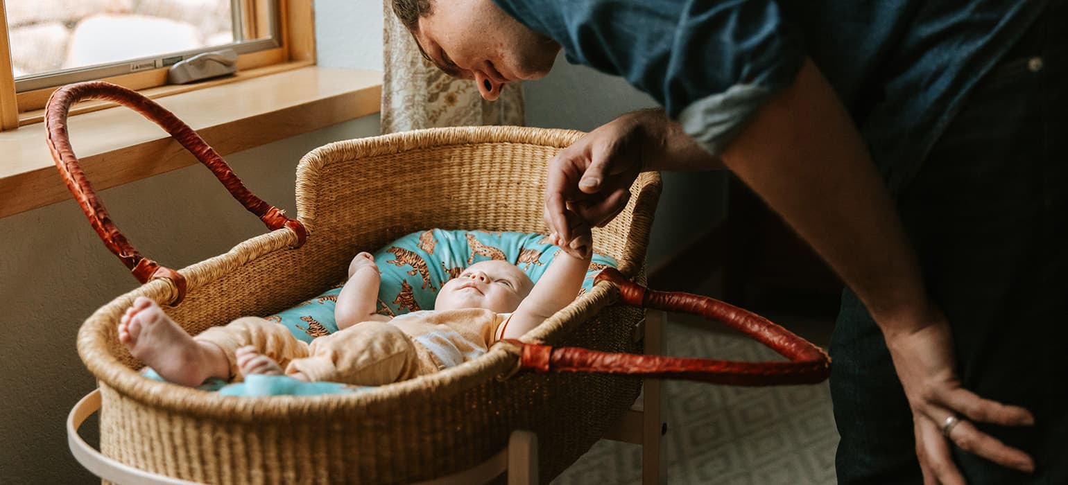 Father looking over his sone in a Moses Basket